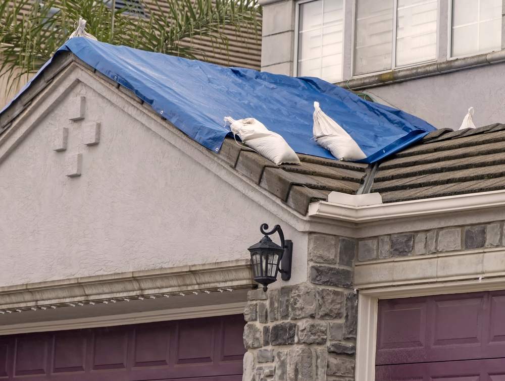A damaged roof partially covered by a tarp.