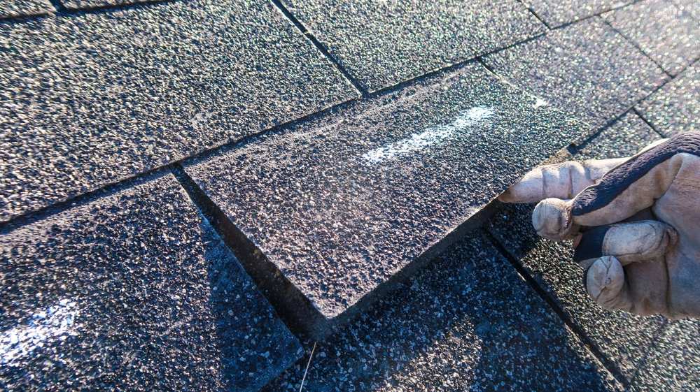 A roofer pulling on a shingle.